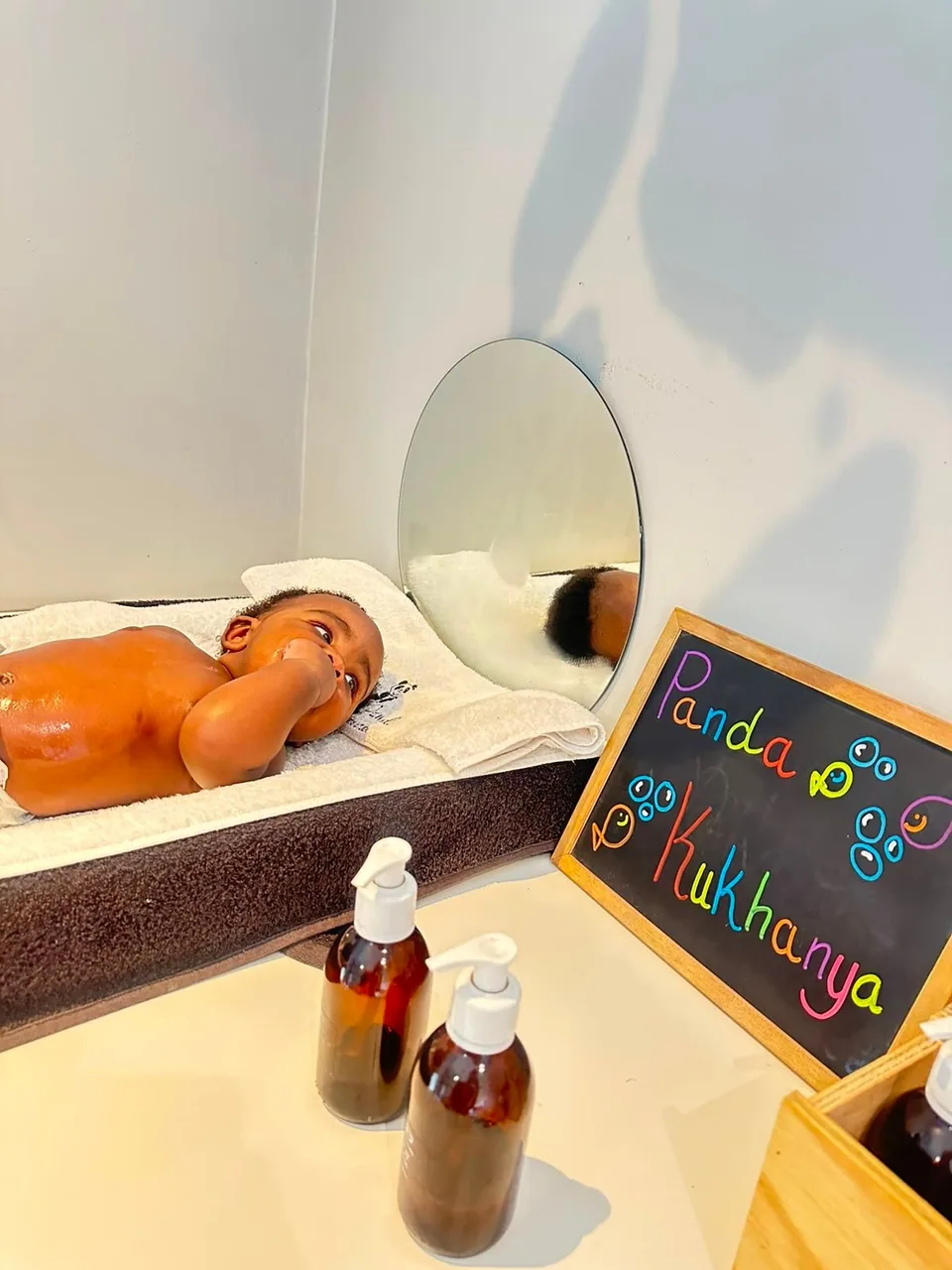 A baby resting on a towel-covered massage bed at Floating Panda
