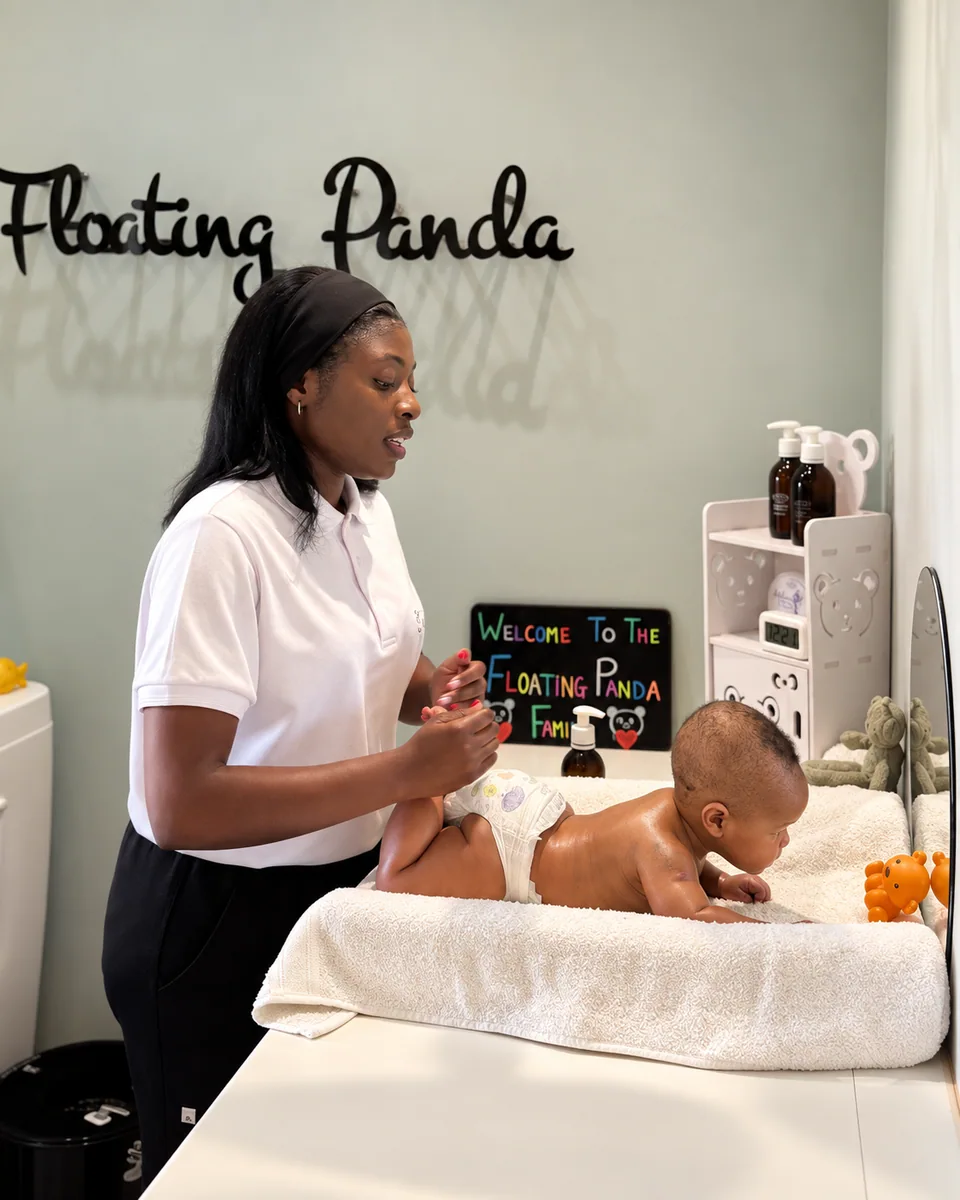 A team member caring for a baby on a towel-covered treatment bed at Floating Panda