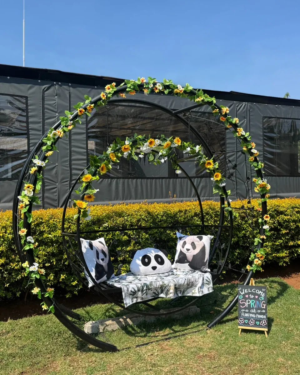 The outdoor hanging seat with panda cushions and a flower-covered frame